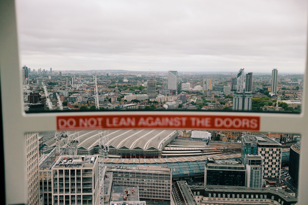 a view of a city from a window with a do not lean against the doors