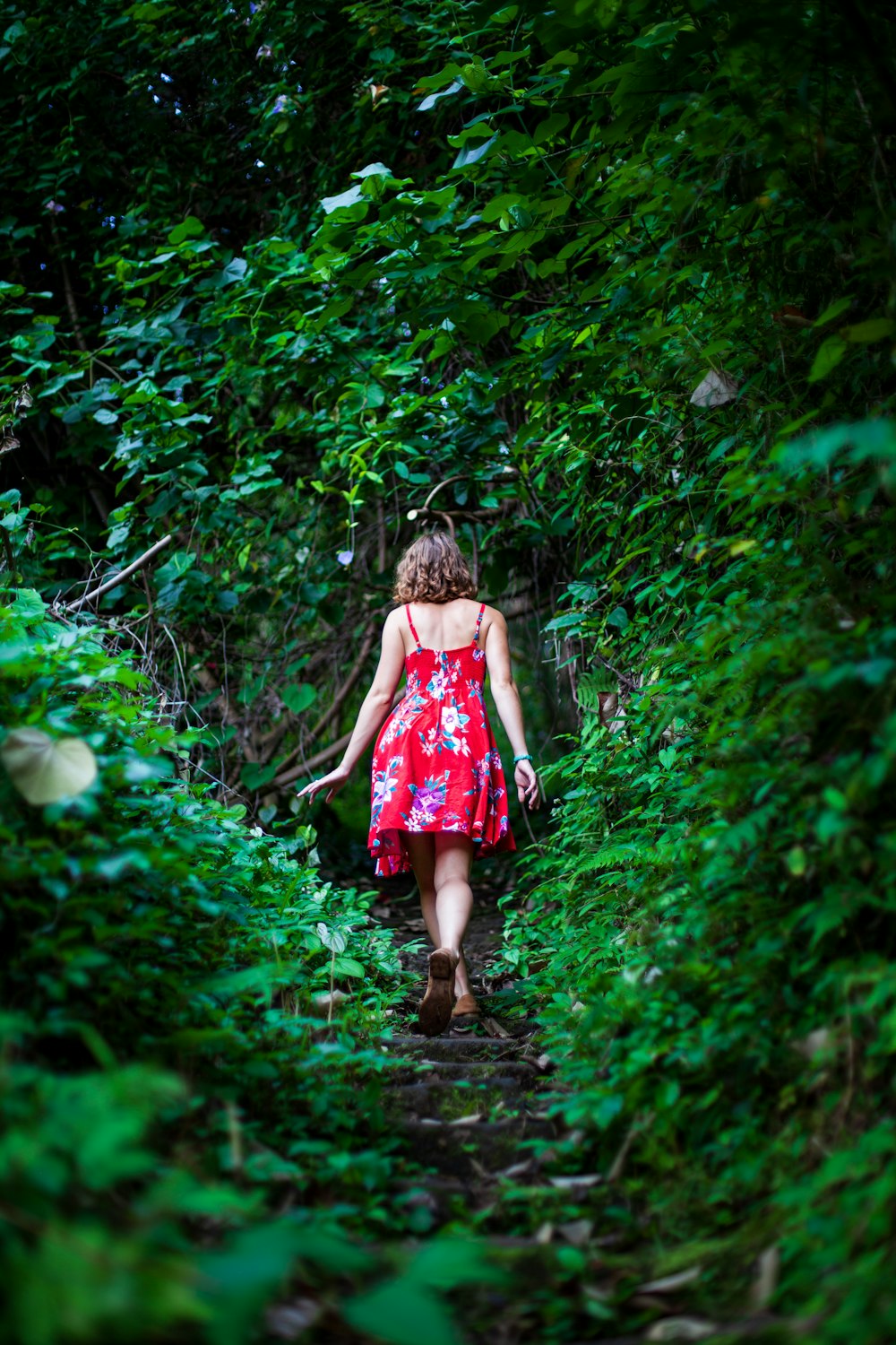a woman in a red dress walking through a forest