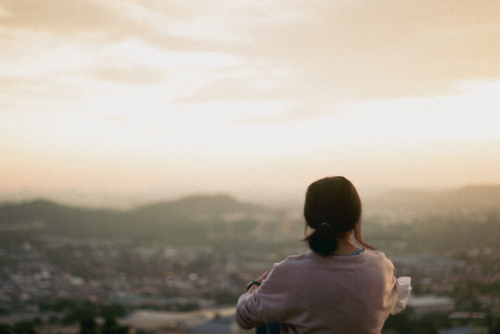 a woman standing on top of a hill overlooking a city