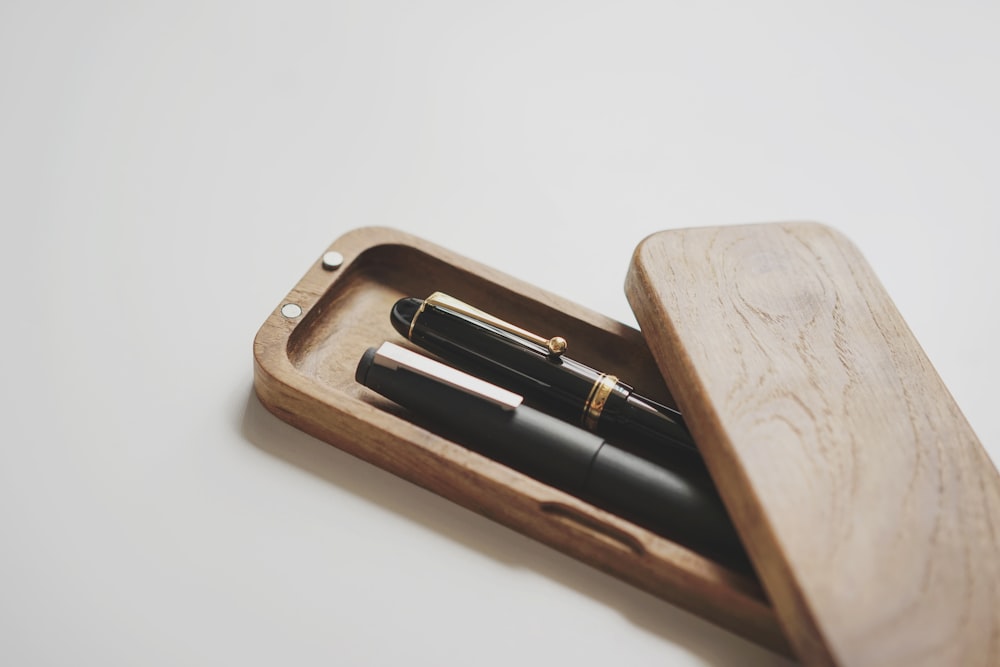 a wooden box with two pens in it