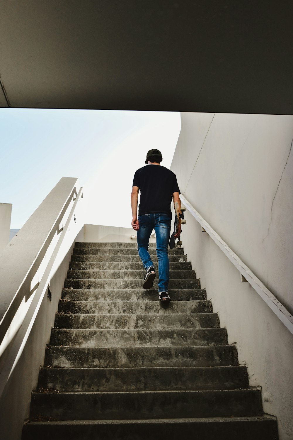 a man walking up a flight of stairs with a skateboard