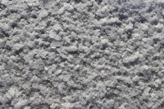 A close-up view of a textured surface covered in coarse, granular white crystalline material, resembling salt or snow.