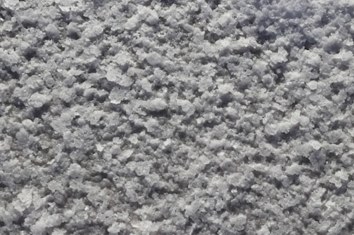 A close-up view of a textured surface covered in coarse, granular white crystalline material, resembling salt or snow.