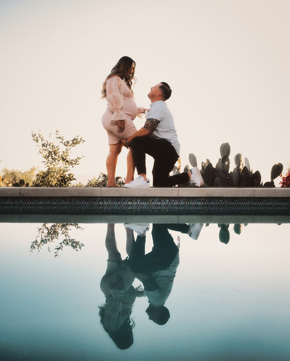 a man kneeling down next to a woman near a pool