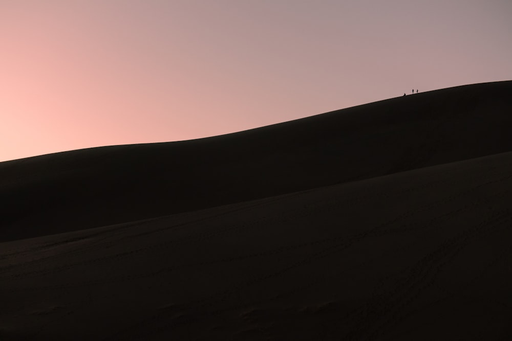 the sun is setting in the sky over the sand dunes