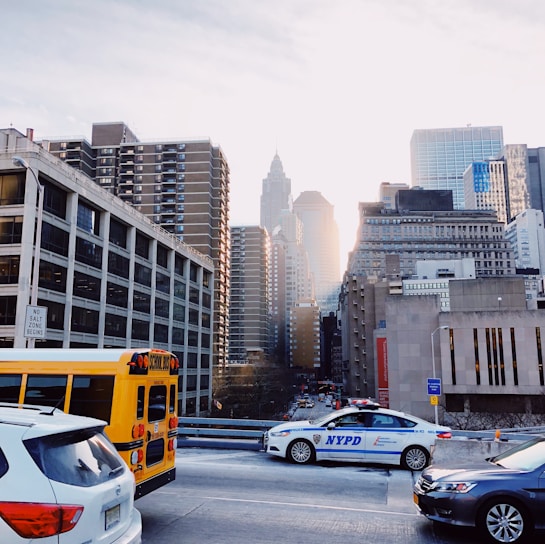 A sleek NYC Sprinters bus parked in front of a bustling New York City skyline at sunset.