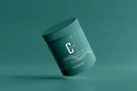 A green cosmetic jar with a minimalist design, featuring the letter 'C' prominently on its front. The jar appears to be floating against a solid green background, creating a sense of simplicity and elegance.