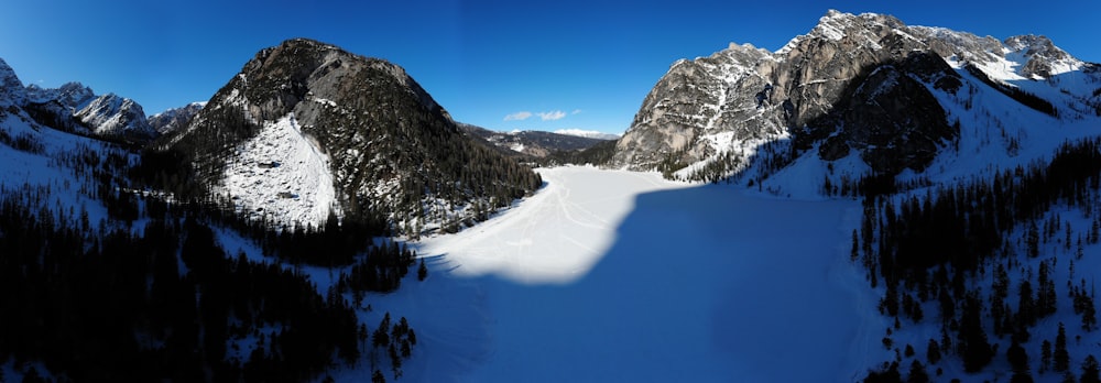 a snow covered mountain range with trees in the foreground