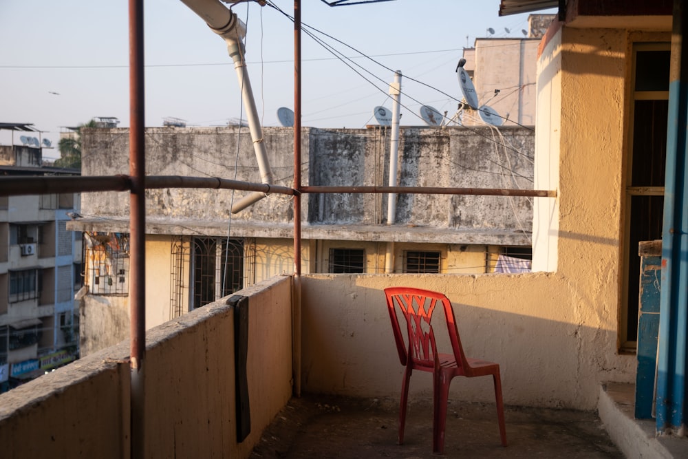 a red chair sitting on top of a balcony next to a building