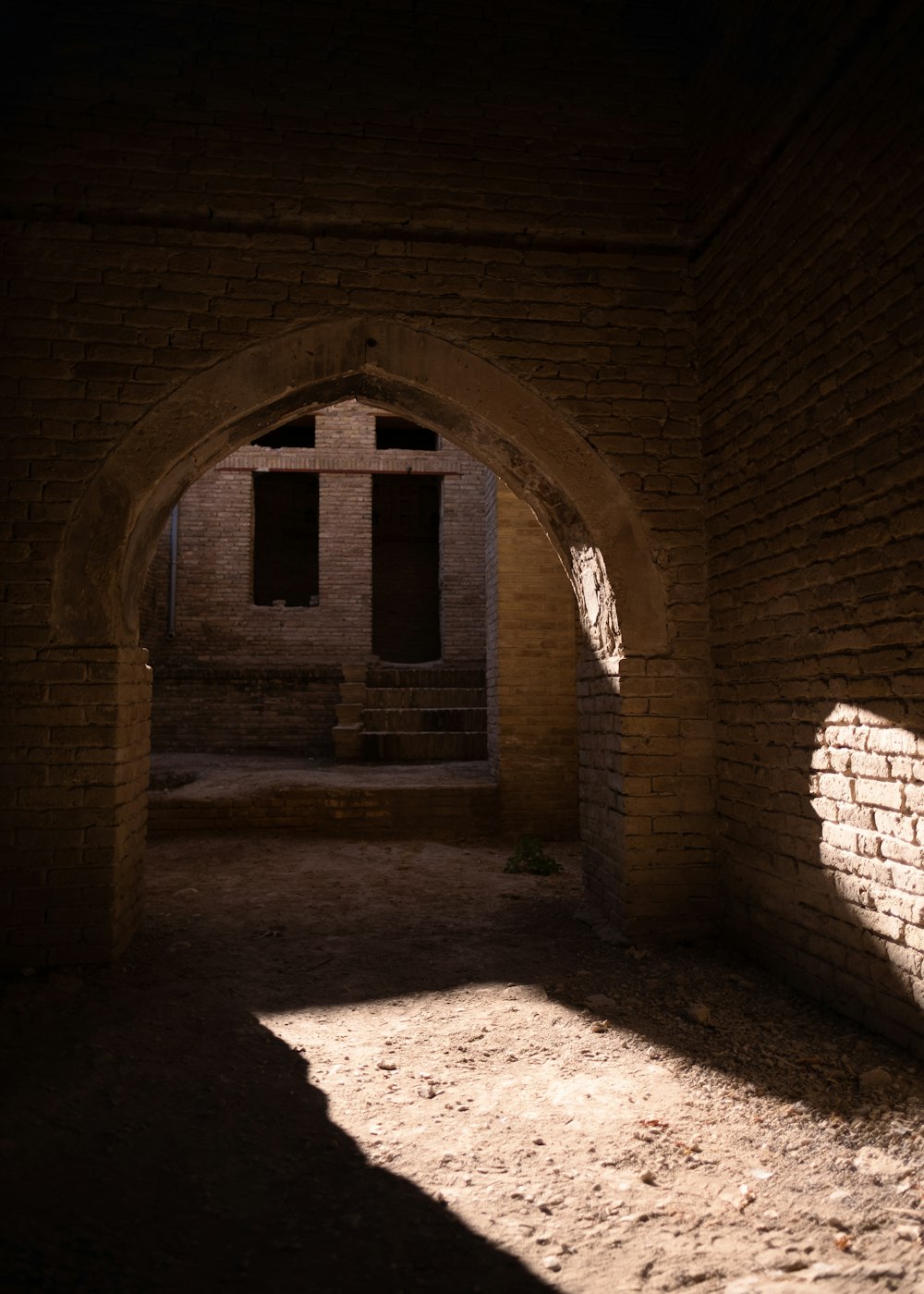 an archway in a brick building with sunlight coming through