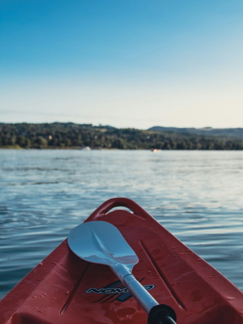 a red kayak with a paddle on a lake