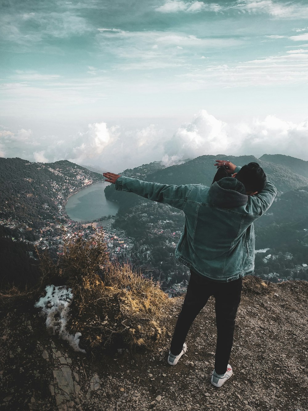 Una persona in piedi sulla cima di una montagna che indica il cielo