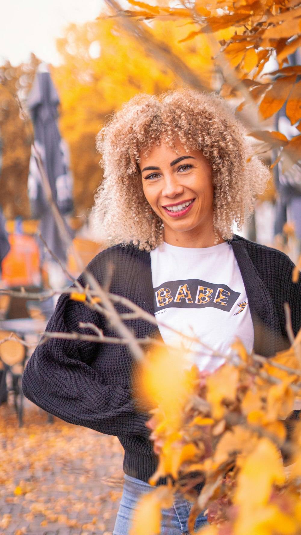 a woman with curly hair standing in front of a tree