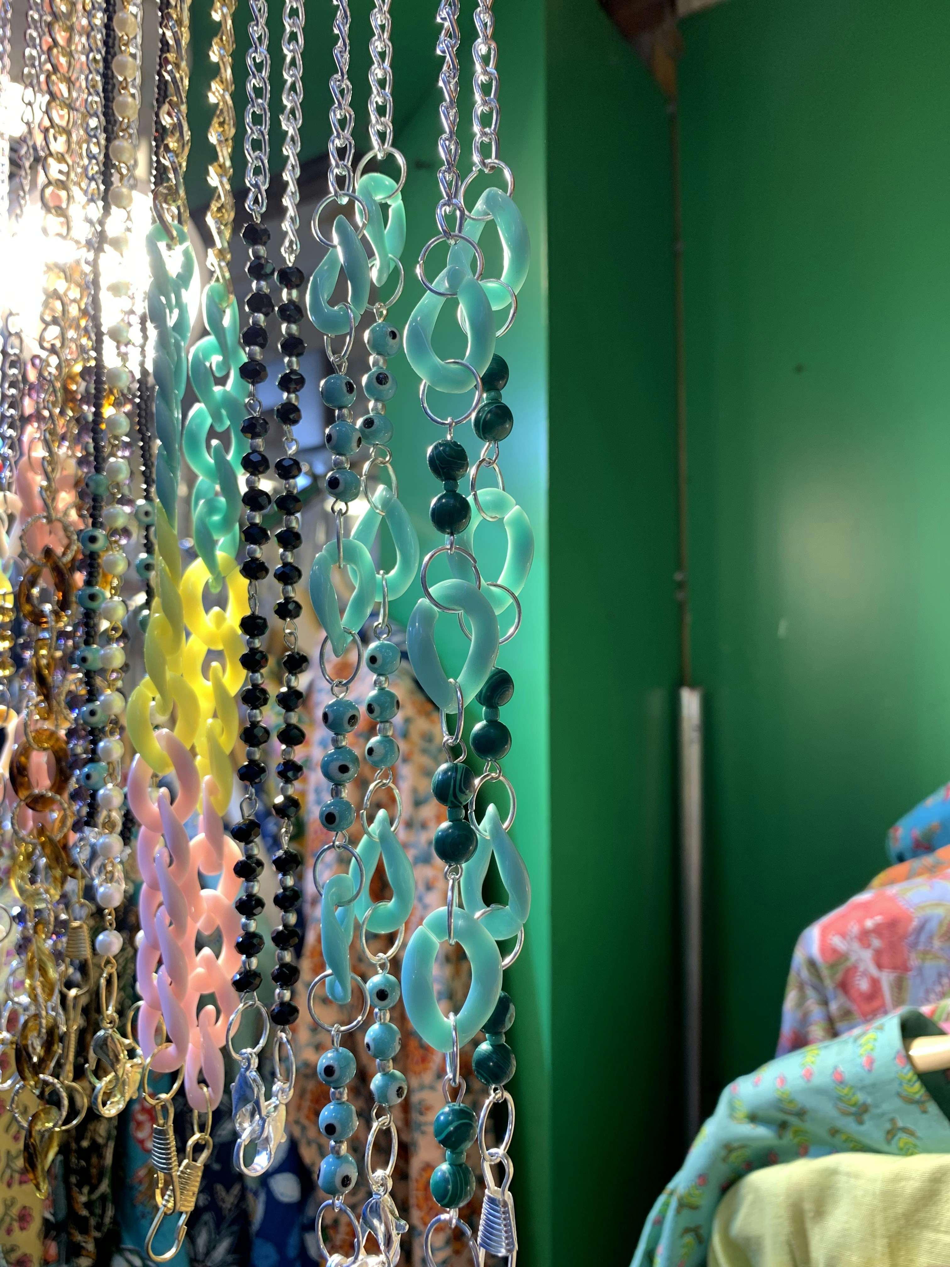 a bunch of necklaces hanging from a green wall
