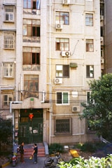 A group of neighbors discussing building maintenance outside their apartment complex.
