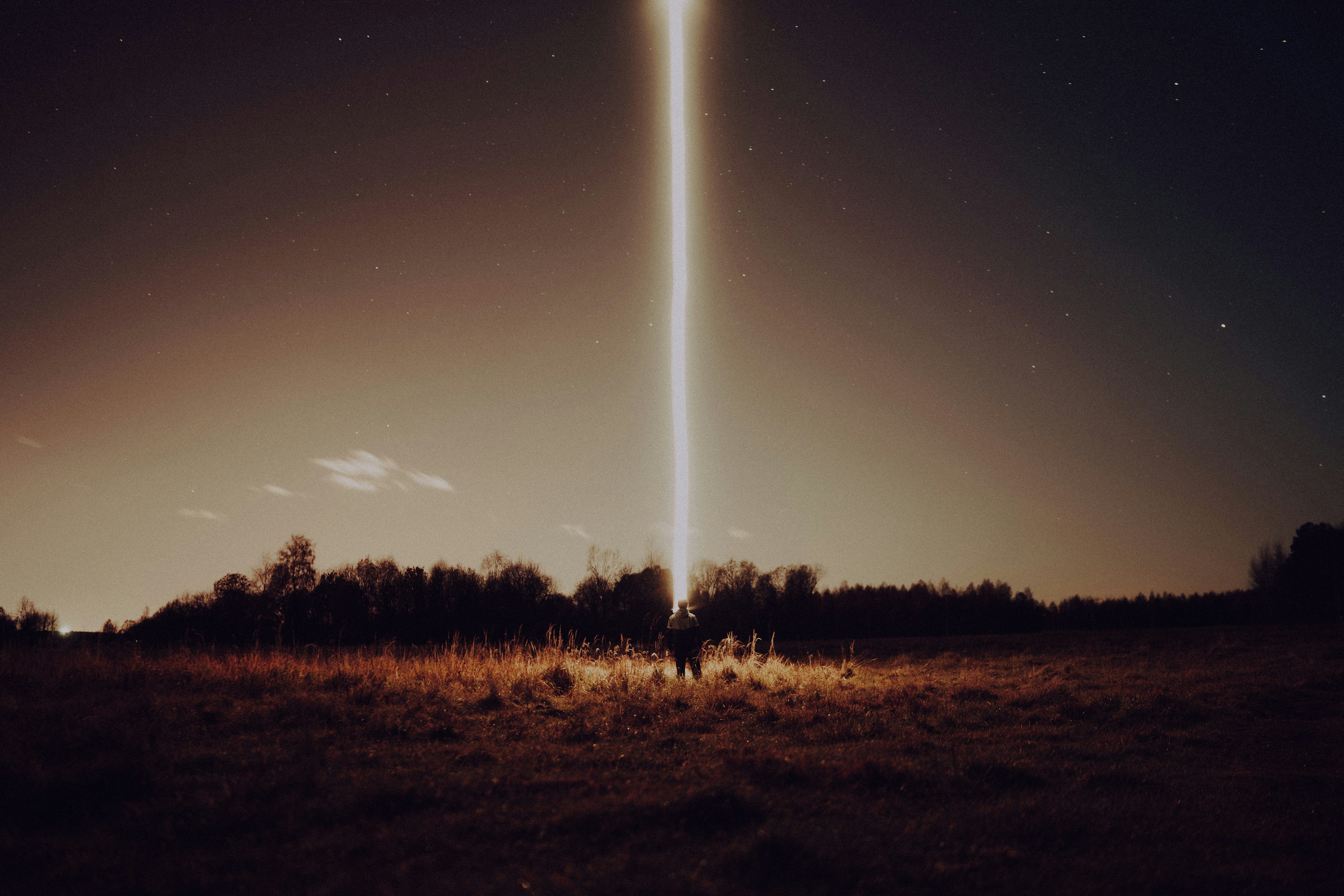 two people standing in a field at night with a large object in the sky