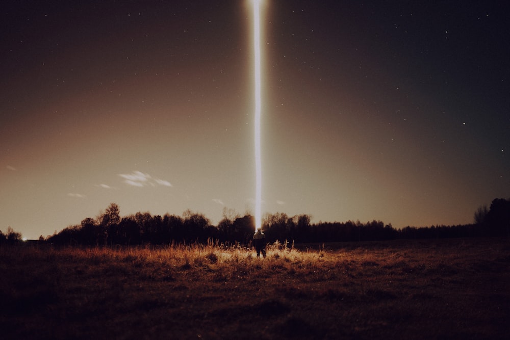 two people standing in a field at night with a large object in the sky