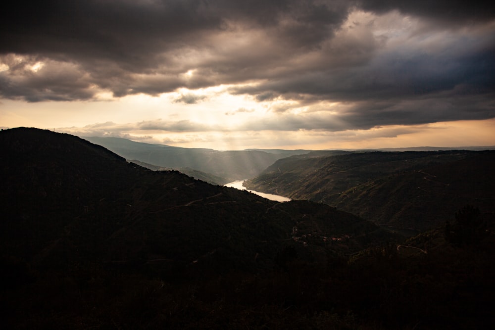 the sun shines through the clouds over a valley