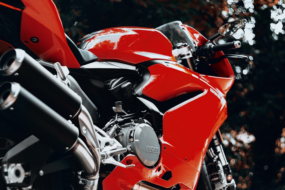 a red motorcycle parked in front of a tree