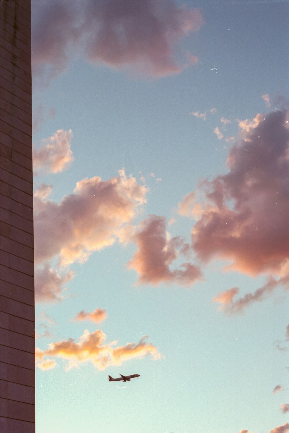 a plane flying in the sky near a tall building