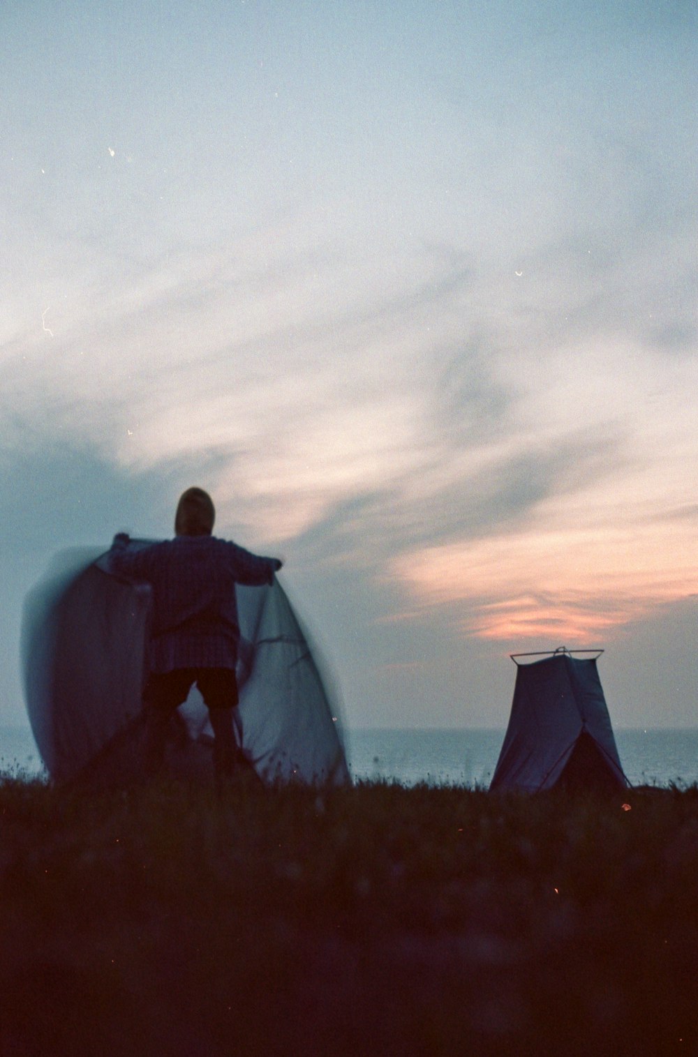 a man standing next to a surfboard on top of a grass covered field