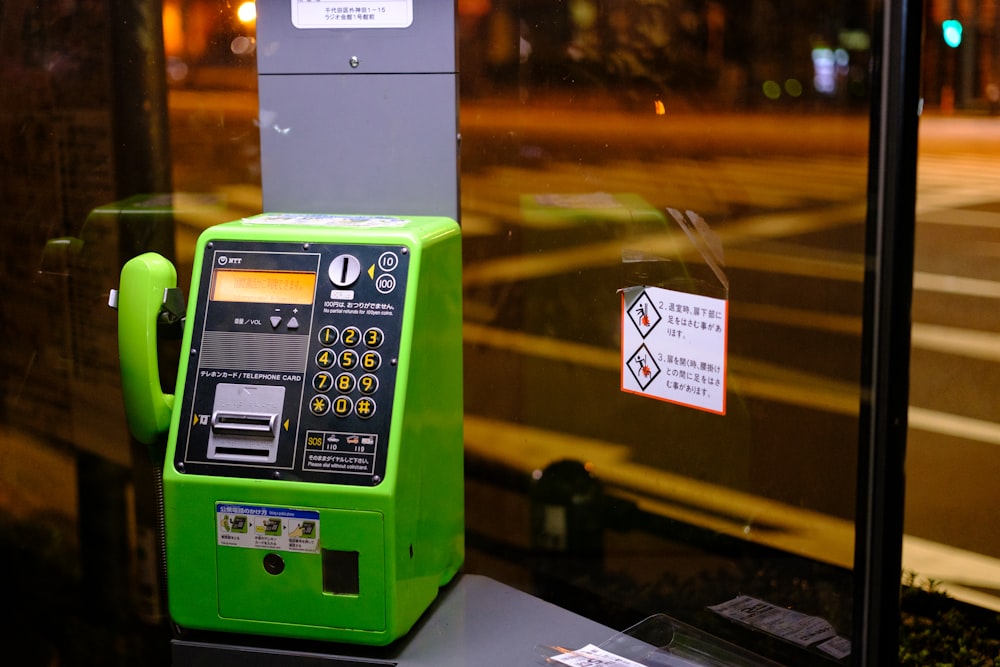 Un teléfono público verde sentado encima de una mesa