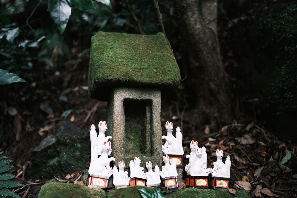 a group of small white figures in front of a moss covered house