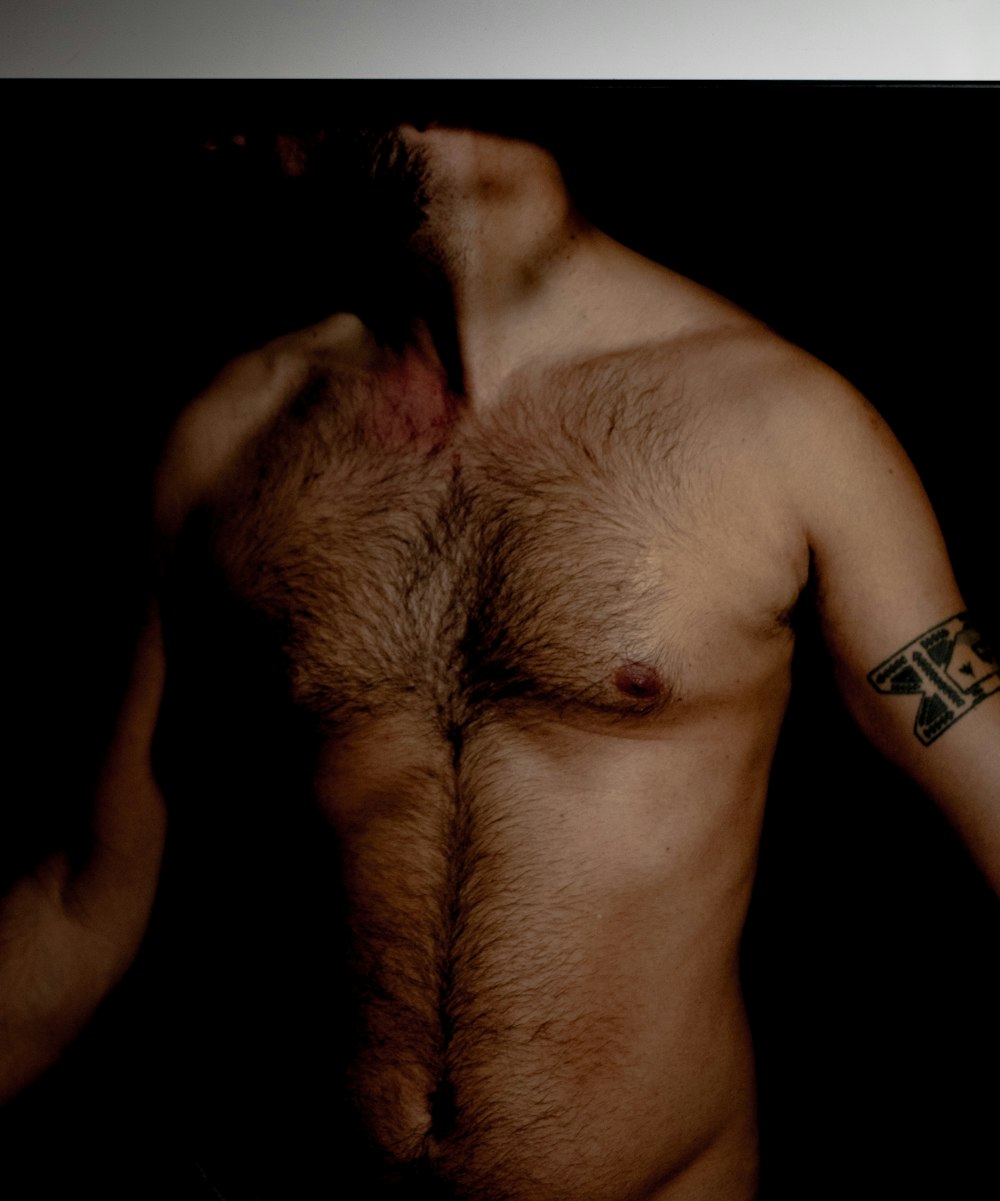 a shirtless man with a cross tattoo on his arm