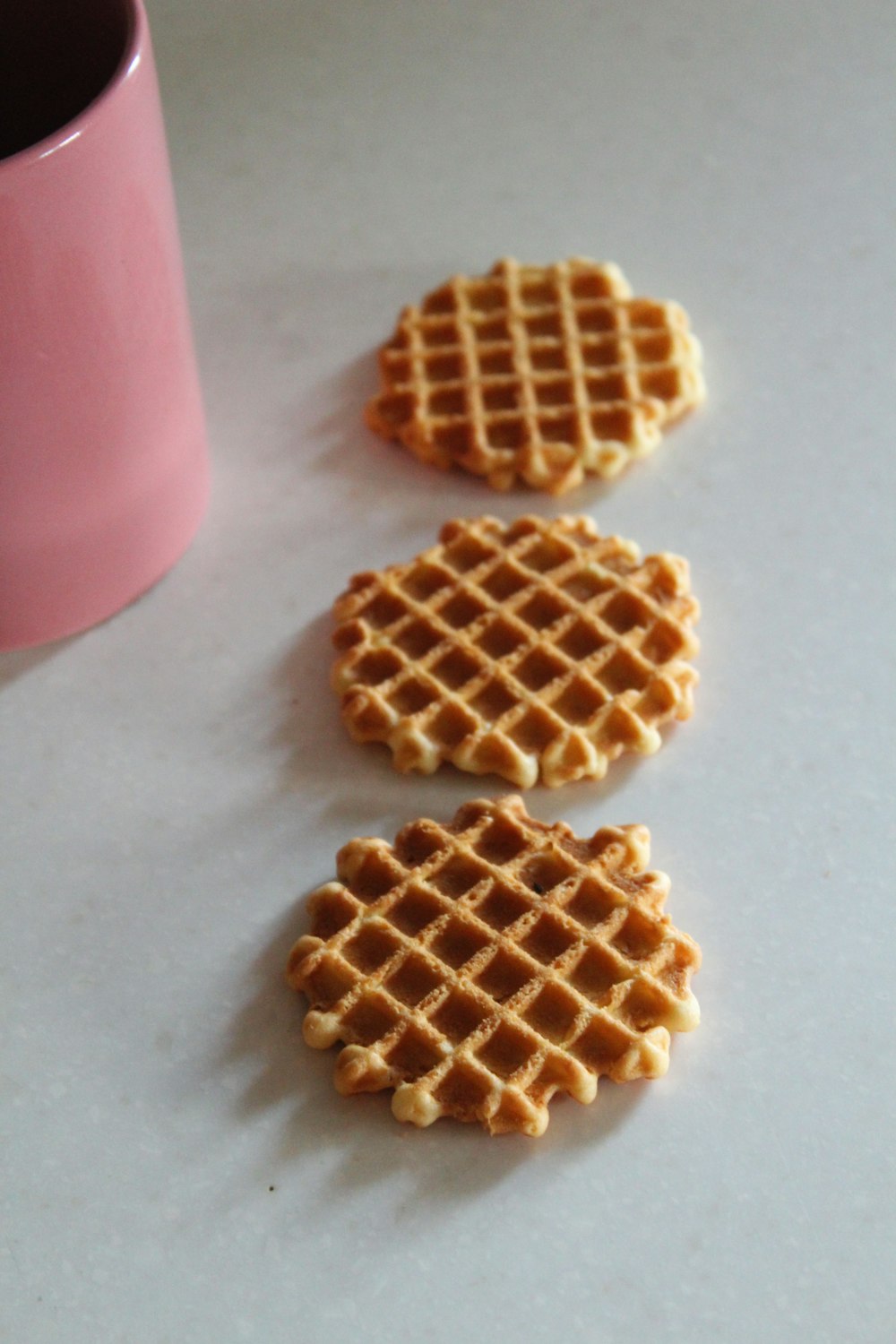 three waffles sitting on a table next to a cup of coffee