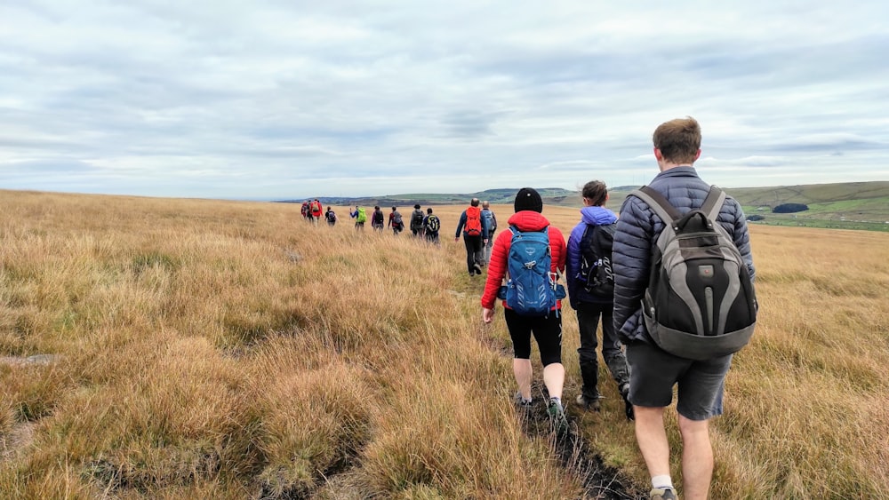 a group of people walking across a grass covered field