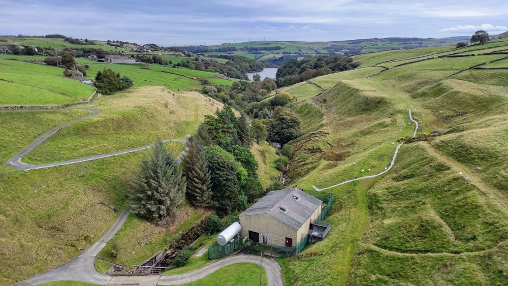 an aerial view of a house surrounded by green hills