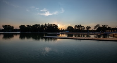 A serene view of Parakrama Samudraya lake at sunset with birds flying low over the water.