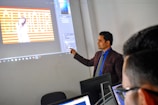 a man standing in front of a projector screen giving a presentation