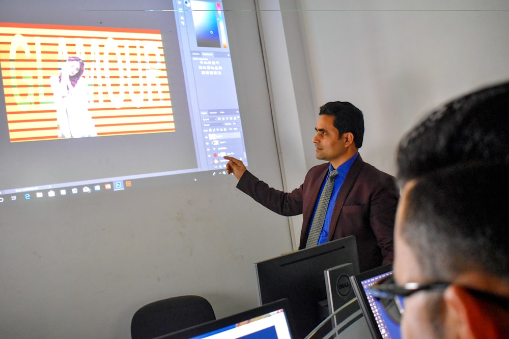 a man standing in front of a projector screen giving a presentation