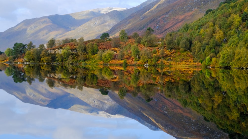 a lake surrounded by mountains with trees in the foreground