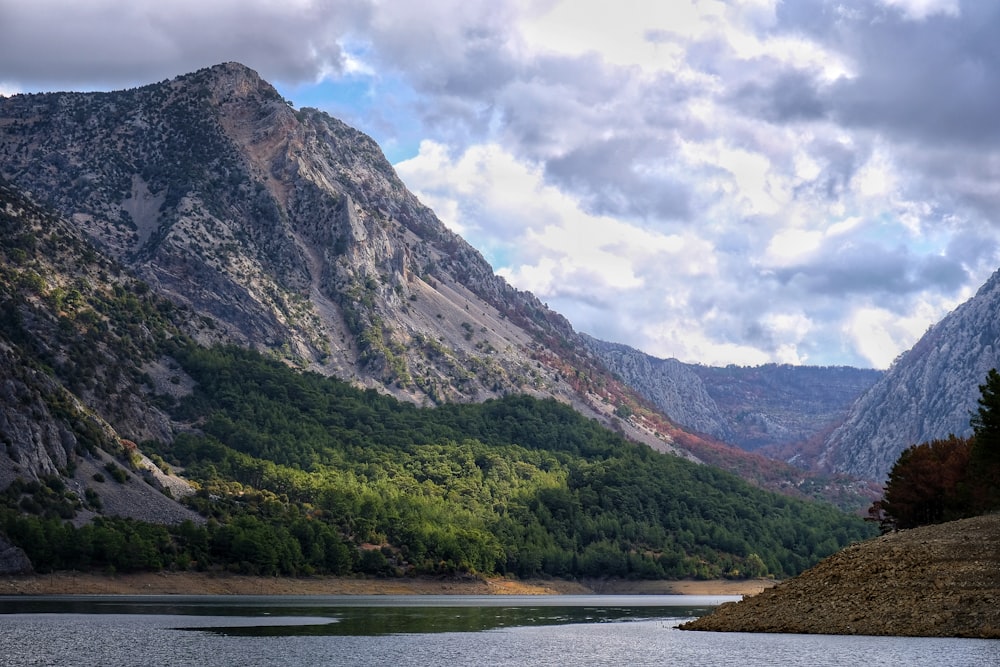 a body of water surrounded by mountains under a cloudy sky