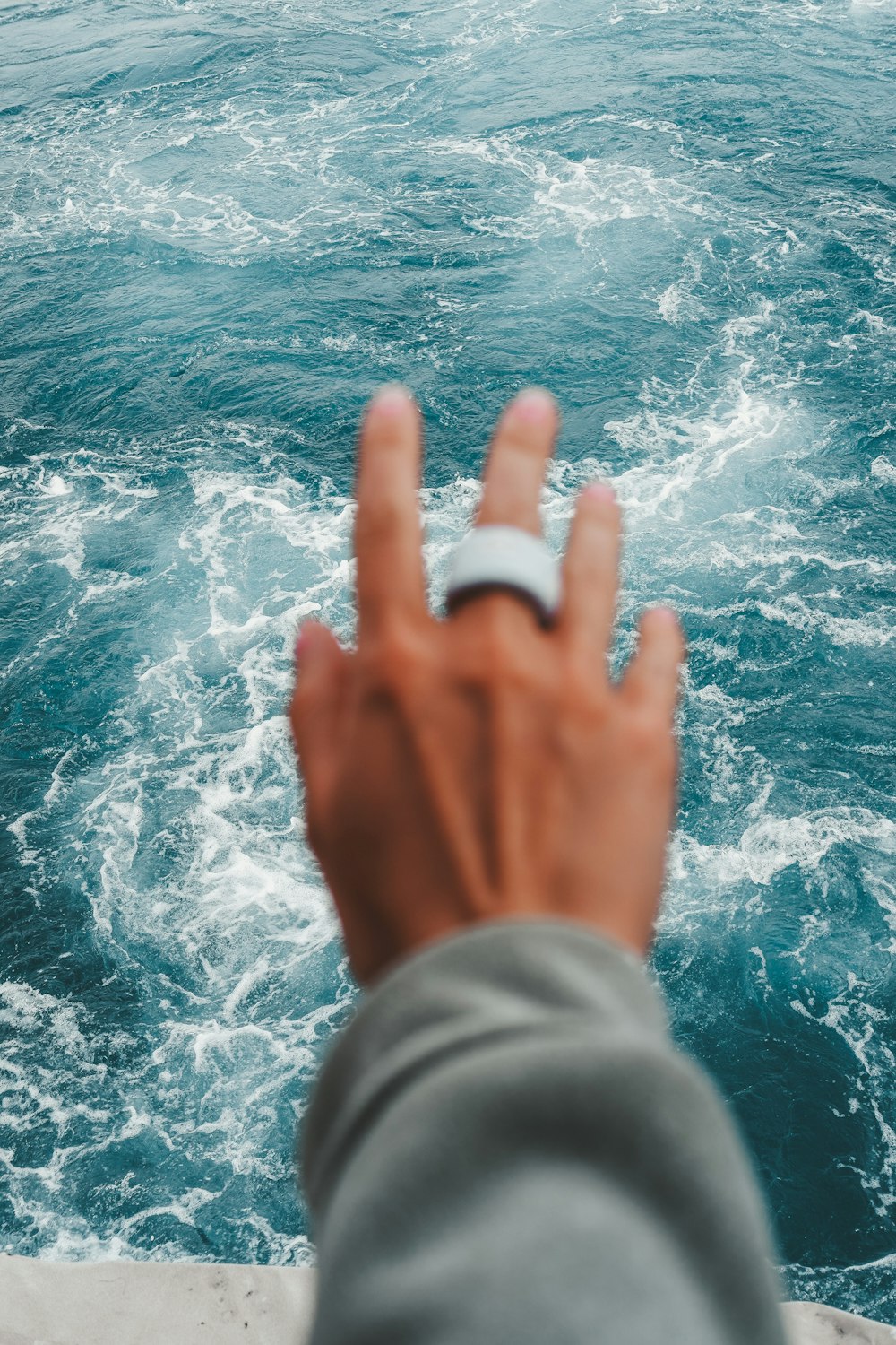 a person holding a cell phone in front of a body of water