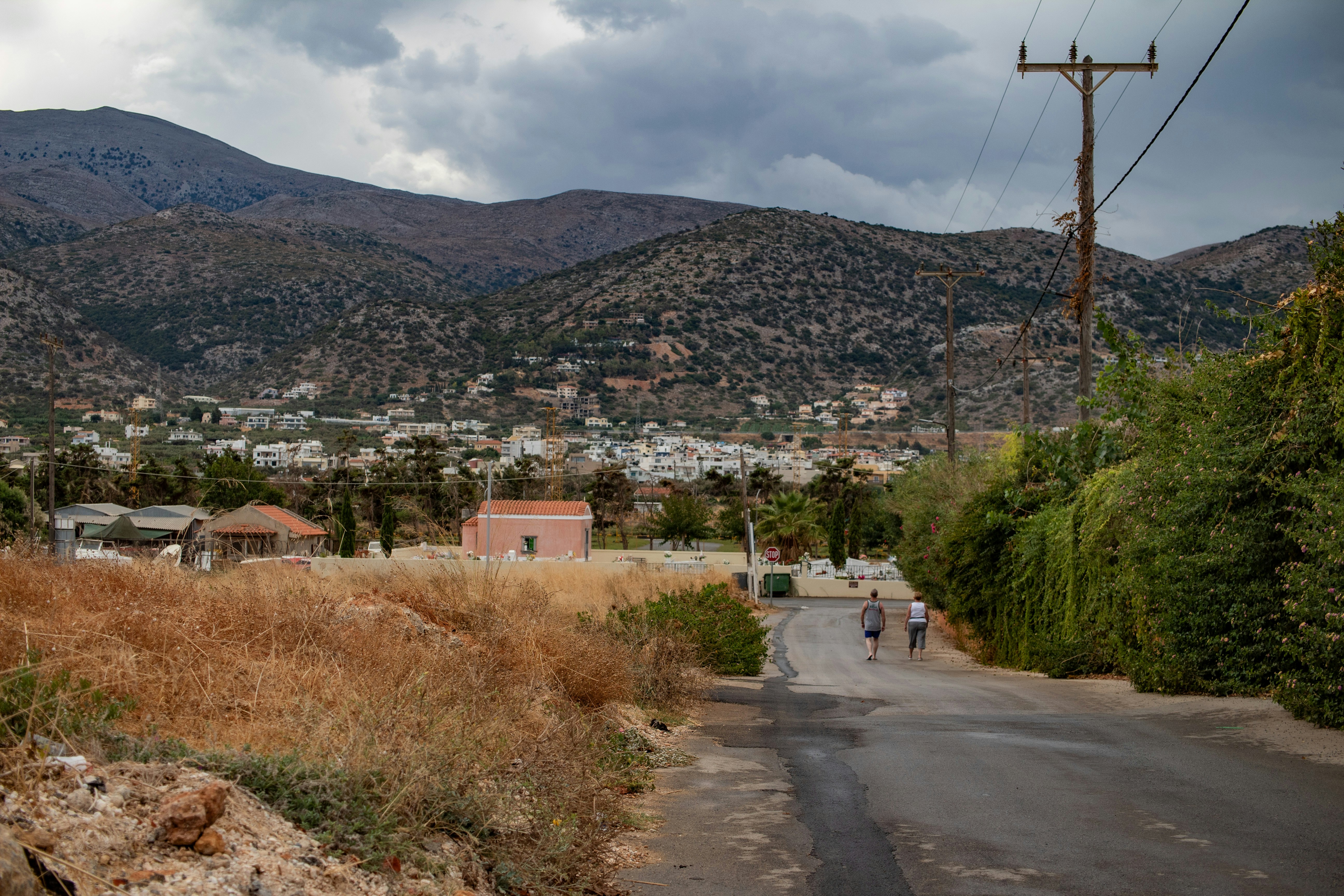 a couple of people walking down a dirt road, 