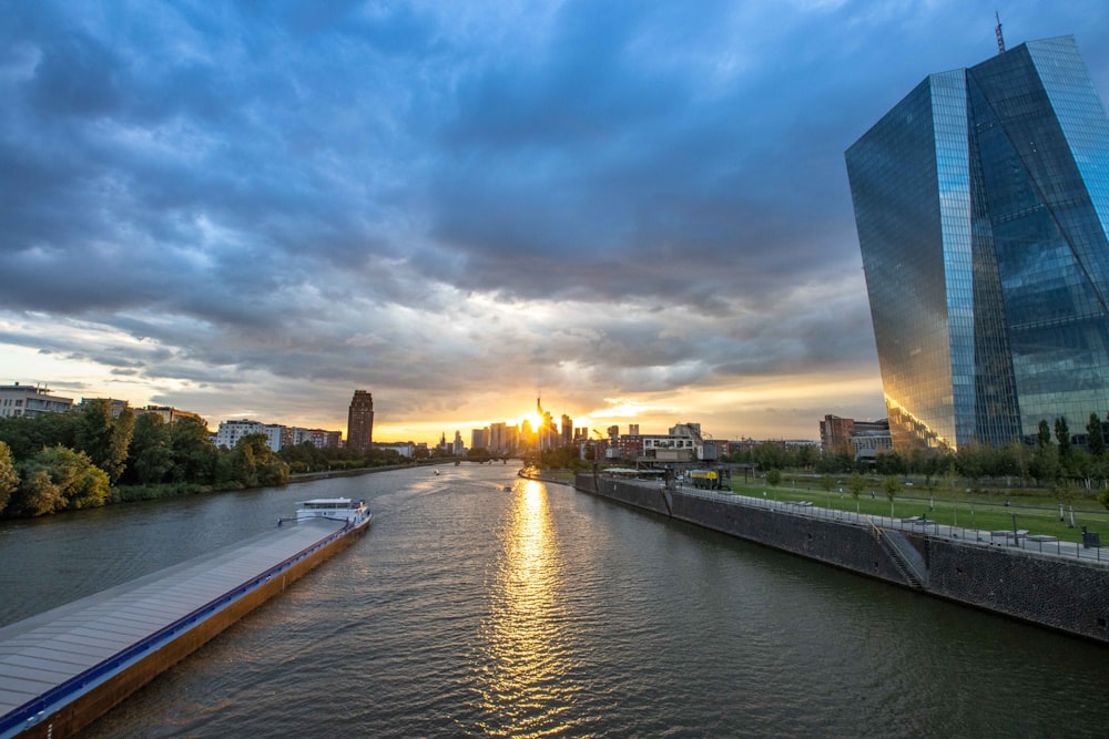 the sun is setting over a river in a city