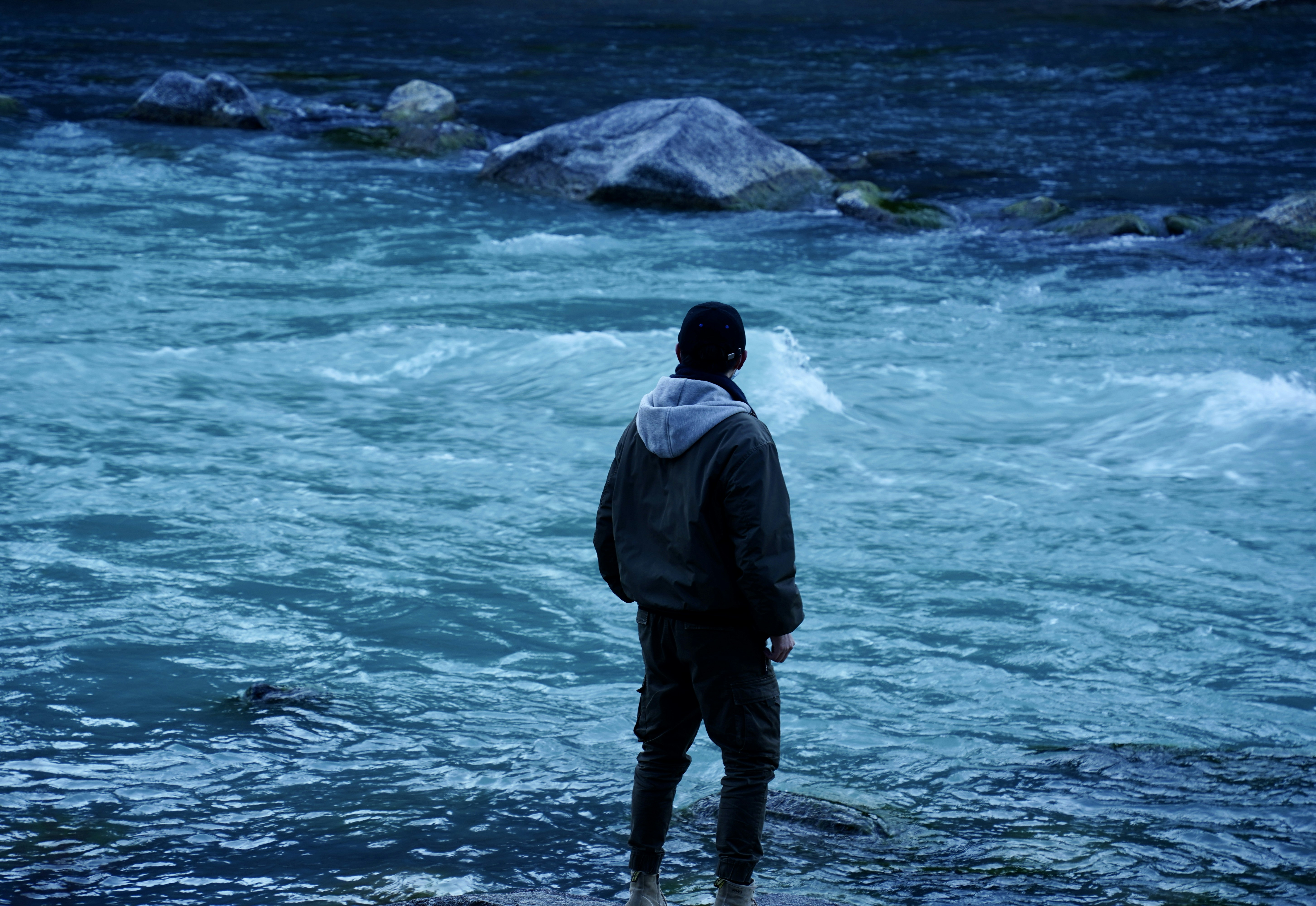 A man standing in a river looking at the water photo – Free River Image ...