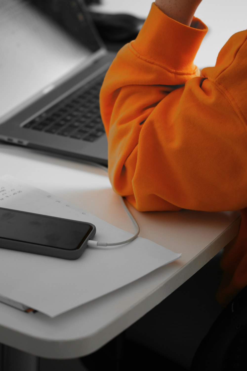 a person sitting at a desk with a laptop and a cell phone