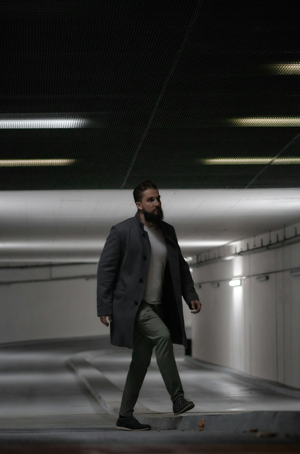a man in a coat is walking through a tunnel