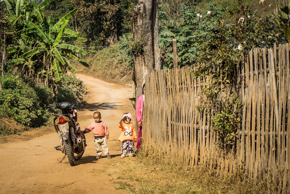 a couple of kids walking down a dirt road