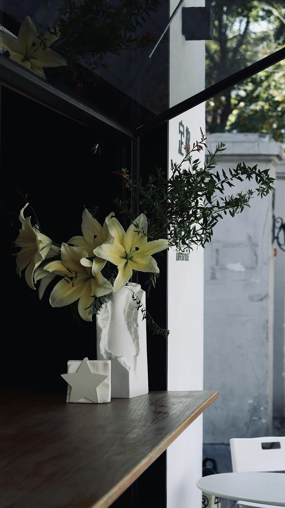 a white vase with yellow flowers on a table