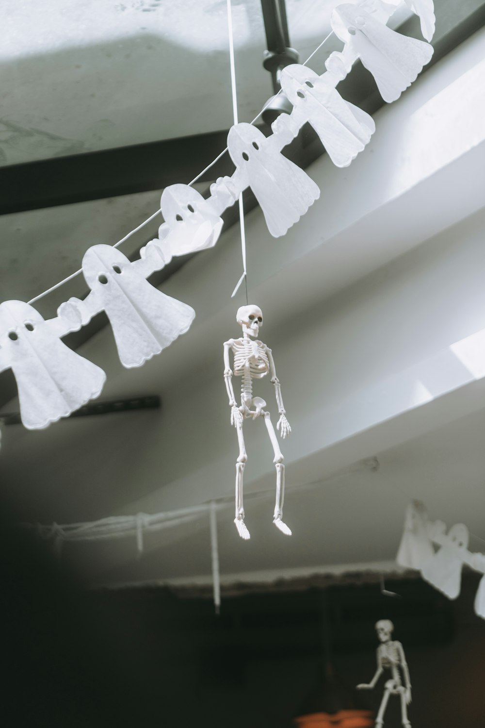 Ein Skelett, das an einer Reihe von Papiergeisterdekorationen hängt