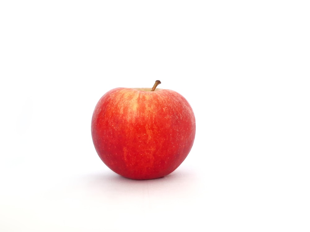Ein roter Apfel sitzt auf einem weißen Tisch