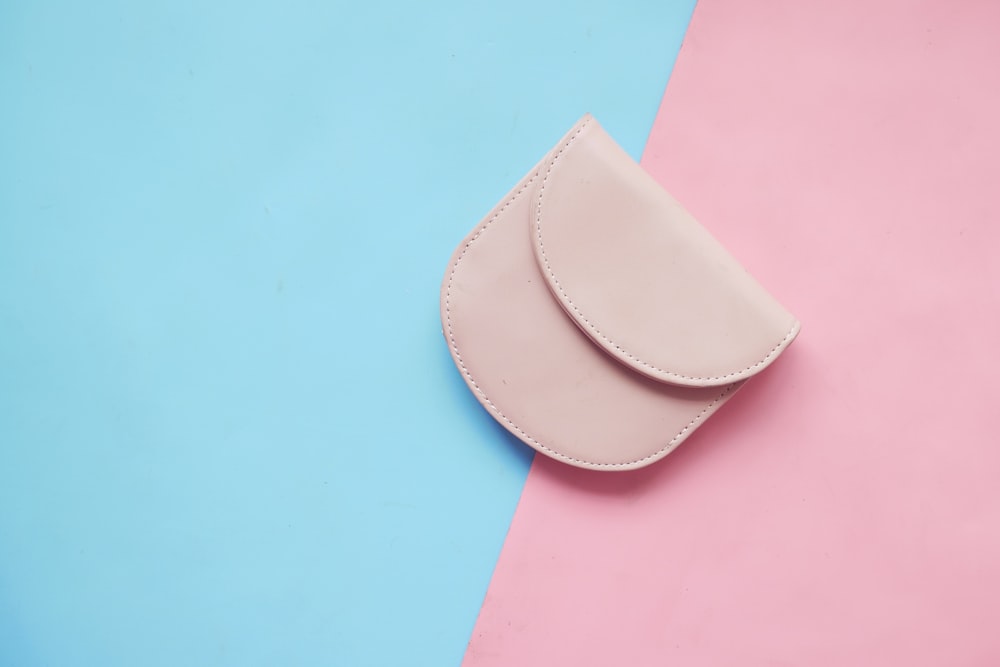 a pink wallet sitting on top of a blue and pink background