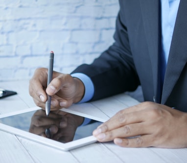 a man in a suit writing on a tablet