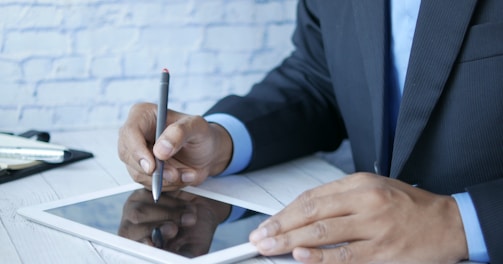 a man in a suit writing on a tablet