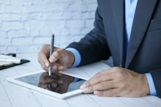a man in a suit writing on a tablet